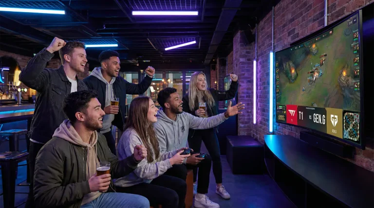 Groupe de jeunes parieurs esport regardant un match League of Legends sur écrans